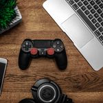 A flat lay photo showcasing a gaming console, laptop, smartphone, and headphones on a wooden tabletop.