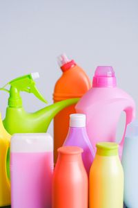Composition of colorful plastic bottles of cleaners with dispenser for everyday routine placed on table against white background in light room